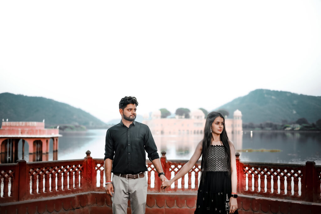 Romantic pre wedding couple holding hands at Jal Mahal Jaipur captured by Vishal Photos Jaipur with a scenic lake and palace backdrop.