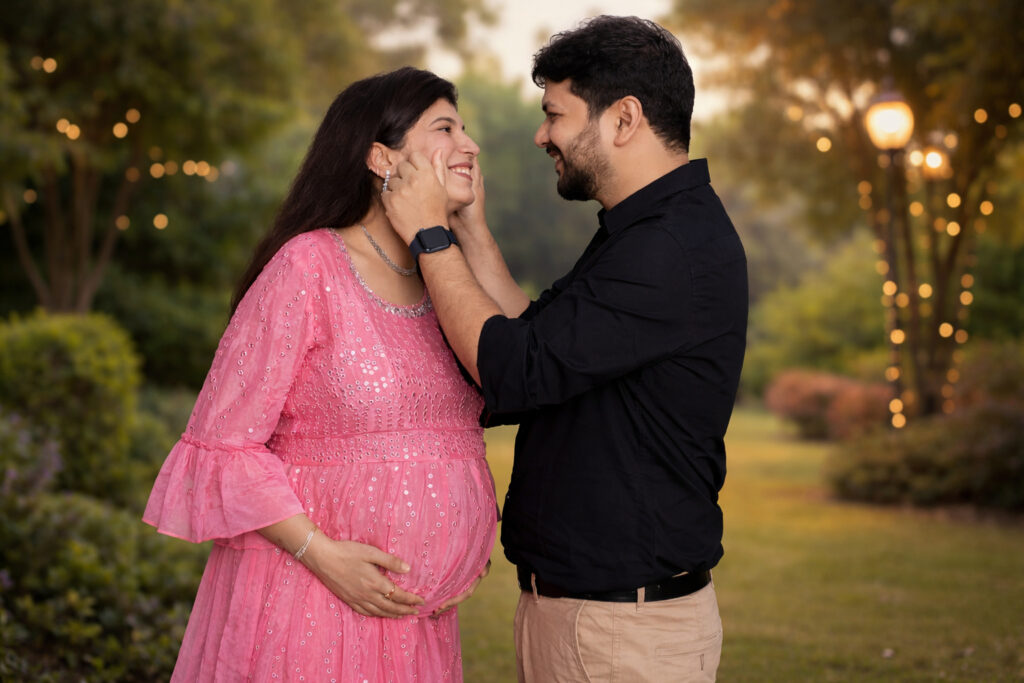 Romantic maternity photoshoot of a couple in a garden setting in Udaipur with soft lights and greenery.