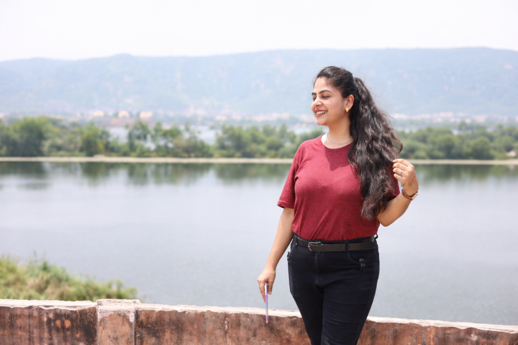 Fashion photoshoot in Jaipur featuring a stylish young woman posing near a scenic lake background during an outdoor fashion photography session.