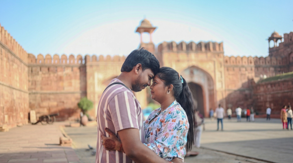 A couple in a romantic embrace during an outdoor pre-wedding shoot at a historic red sandstone fort in Rajasthan, captured by Vishal Photos.