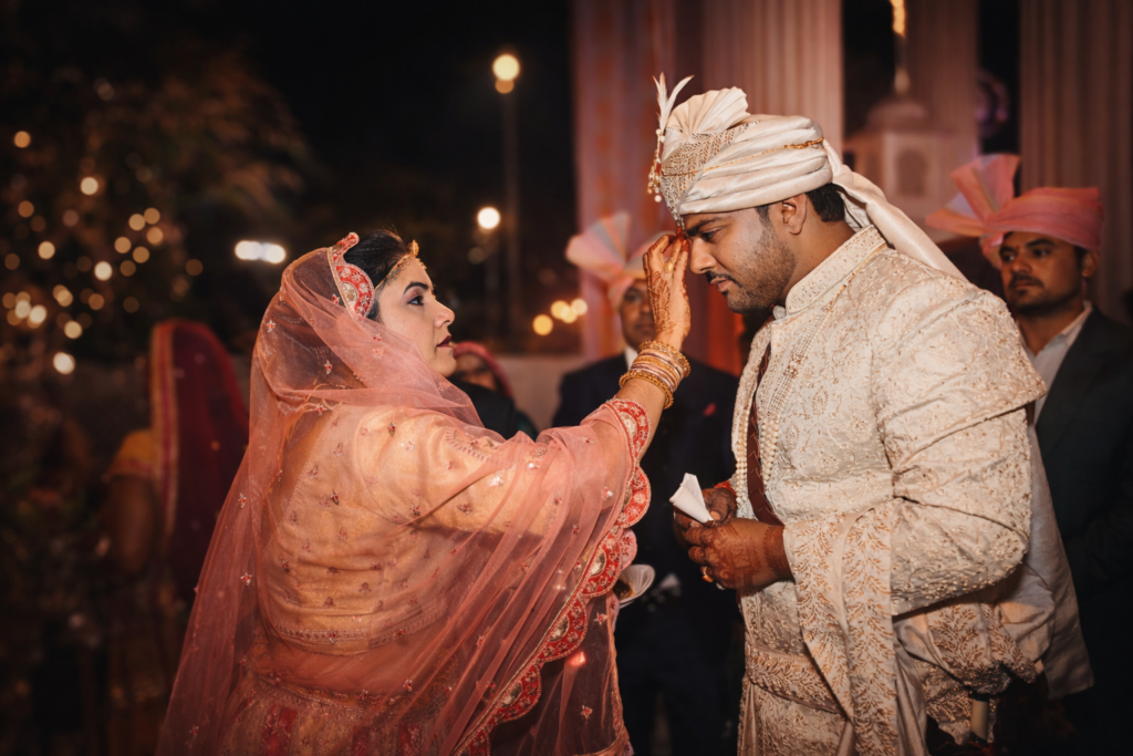 Emotional Indian wedding moment where a mother applies tilak to the groom during a traditional ceremony, captured by a professional wedding photographer in Jodhpur.